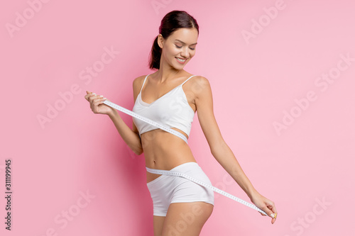 portrait of beautiful attractive nice charming lady with slim athletic body stand isolated over pink background, look down, wearing white underwear