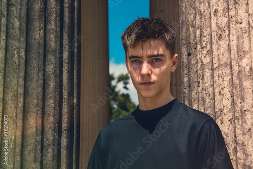 portrait of a young man standing between ancient columns