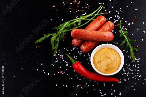 Sausages with mustard on a black background
