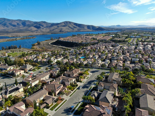 Aerial view of identical residential subdivision house with big lake and mountain on the background during sunny day in Chula Vista, California, USA.