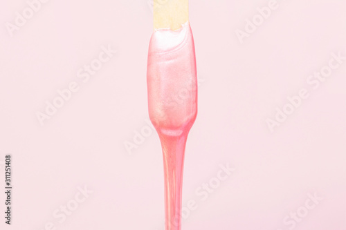 liquid wax for pink depilation drains from the stick. The concept of depilation, waxing, smooth skin without hair.