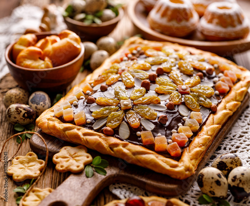 Mazurek pastry, traditional Polish Easter cake made of shortcrust pastry, chocolate cream, candied fruit, nuts and almonds on the holiday table, close-up. Very sweet dessert, Easter treat