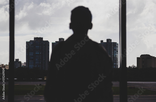 joven mirando hacia los edificios por la ventana en dia nublado