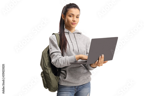Cute female student holding a typing on a laptop and looking at the camera
