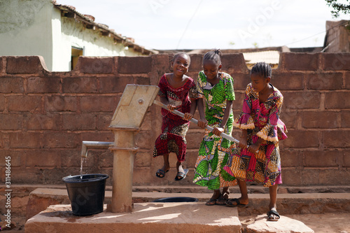 Three Little African Girls Having Fun While Pumping Water At The Borehole