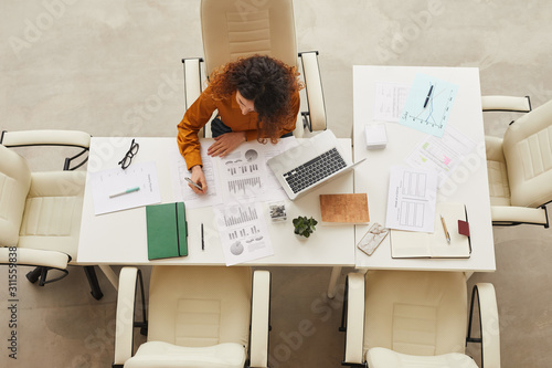 Young businesswoman with curly hair working alone in modern office horizontal from above shot