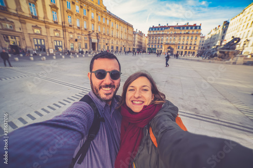 happy tourists traveling in France taking selfie photo in Lyon city, in front of the view of the Saone river, Saint Georges church and bride, and Notre-Dame basilica, in Lyon, France
