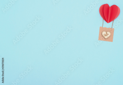 Valentine's Day blue background with red heart balloon with craft basket with wooden heart on it. Valentine greeting card. Flat lay style with copy space. Love and happiness concept. Wedding card.