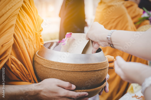 People give alms to buddhist monk when New year is coming. It is Asian traditional. Person offer food and put in monk alms bowl. People do good thing to create positive karma for themself, make merit