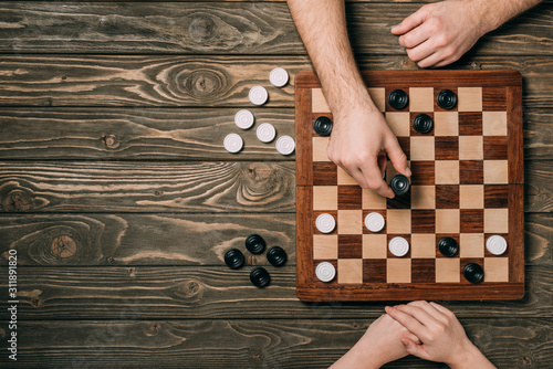 Top view of couple playing checkers on wooden background