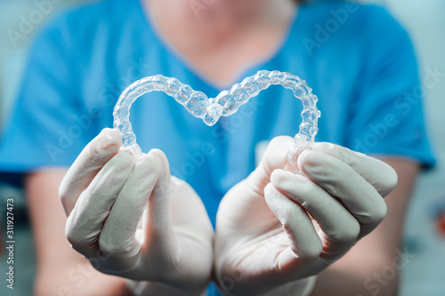 Female doctor holding two transparent heart-shaped dental aligners