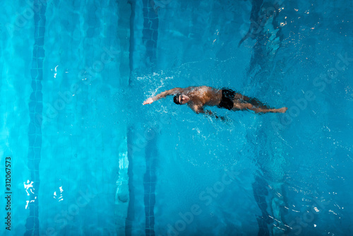 top view of handsome swimmer doing backstroke swimming in swimming pool