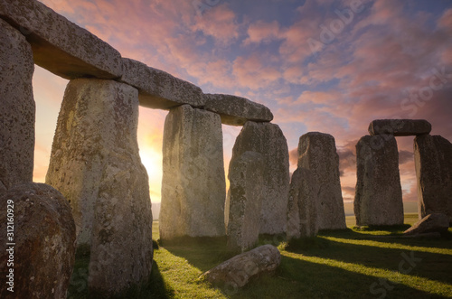 Inside the Stonehenge Circle of Stones with a Sun Rays Filtering Through the ArchesDramatic Sky Sunrise behind it