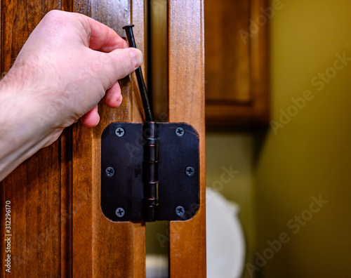 Oiled bronze door hinge with pin being removed