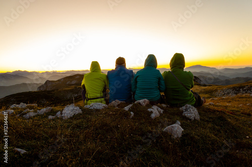Abendpanoama am Berg mit vier Personen von hinten und bunten jacken