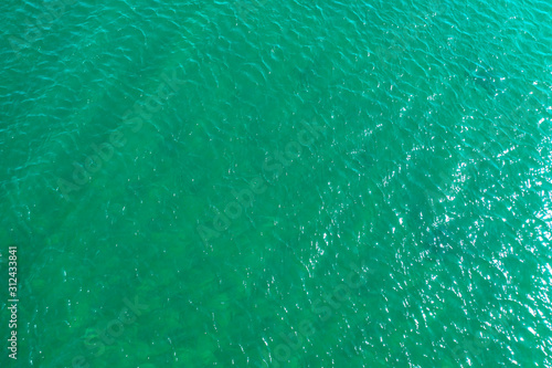 aerial view of the texture of the surface of turquoise water with sun reflections