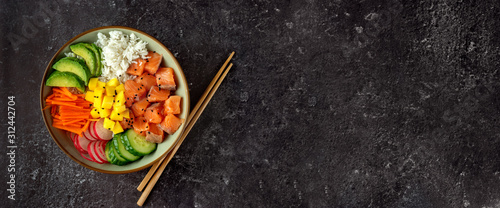 Top view of poke bowl with salmon and avocado on dark background