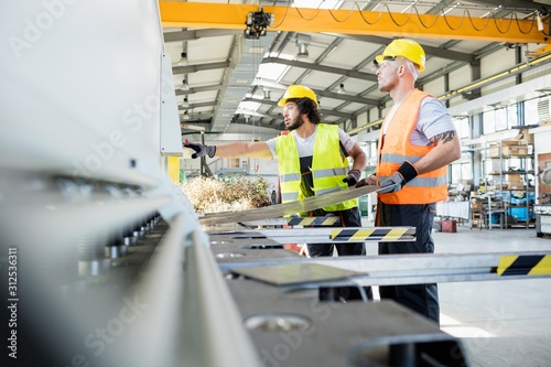 Male manual workers manufacturing sheet metal at industry