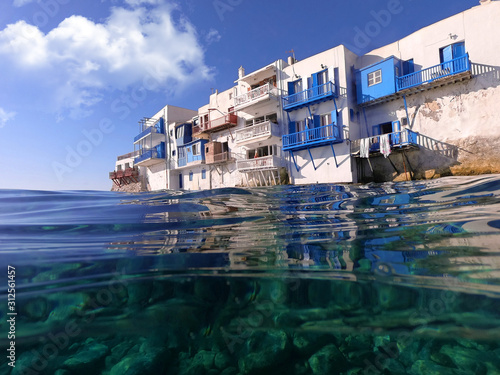 Underwater split photo of iconic landmark picturesque whitewashed Little Venice in main village of Mykonos island in emerald clear sea, Cyclades, Greece