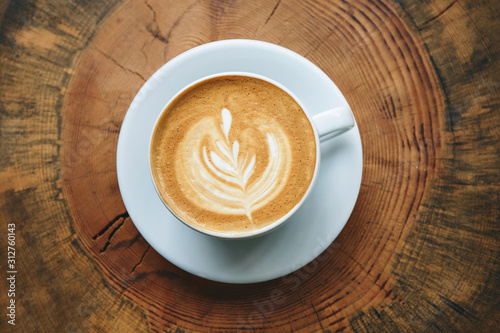 Close up of fresh aromatic cappuccino coffee on a wooden surface.