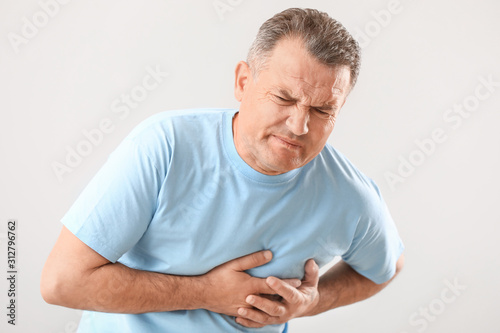 Mature man suffering from heart attack on white background