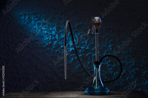 Preparing a hookah for using. Hookah on blue background. East smoking hookah with neon light. Trendy shisha for relax