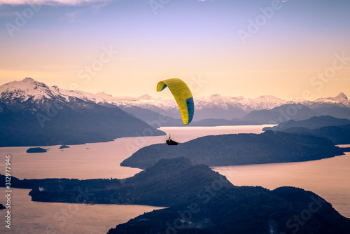 Paragliding over Nahuel Huapi lake and mountains of Bariloche in Argentina, with snowed peaks in the background. Concept of freedom, adventure, flying