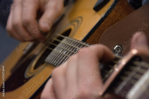 Guitar deck and guitarist hands closeup. Capo on the fretboard of a guitar. Blurred guitar background