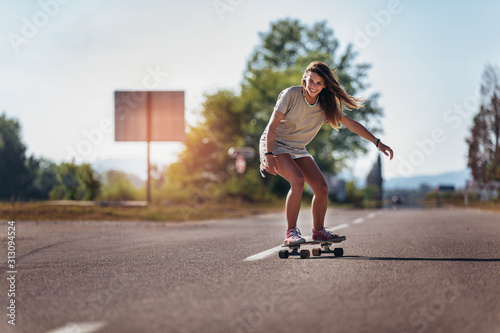 Sporty woman riding on the skateboard on the road. Longboarding, female.