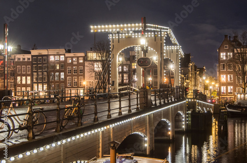 Magere Brug, Skinny bridge, illuminated at night over the river Amstel in the city centre of Amsterdam, The Netherlands