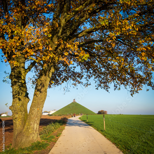 Famous Lion’s Mound (Butte du Lion) monument in Waterloo, framed by a tree in autumn colors