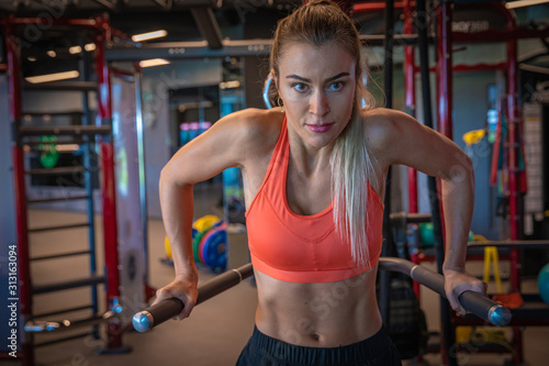 Young sporty woman strengthens with dumbbells in gym