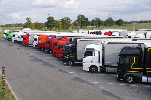 Different types of trucks in a crowded parking lot off the highway.