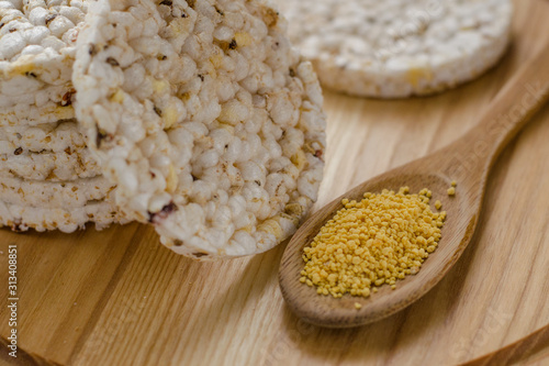 Soy lecithin in a wooden spoon on a wooden backgroundand round multigrain rice cakes.