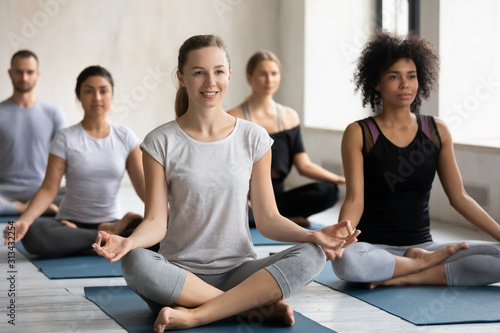 Smiling woman practicing yoga at group lesson, Easy Seat exercise