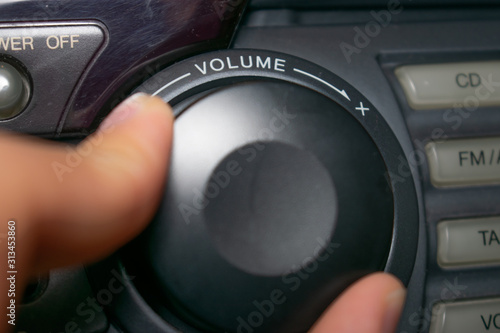 A person turning the volume wheel up or down (the focus is on the word "volume" written on the device)