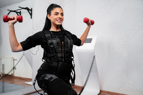 Woman working out with dumbbells in ems suit 