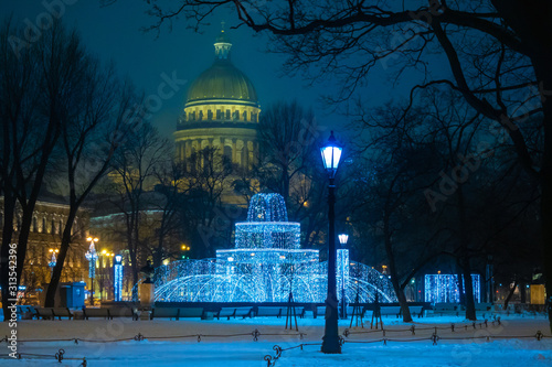 Saint Petersburg. Russia. View of St. Petersburg at Christmas. Fountain of lights on St. Isaac's square. The fountain is decorated with garlands. Isaakievsky cathedral. Lights of the evening city.