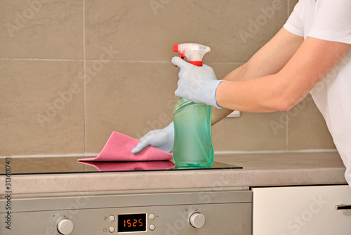 Woman in gloves cleaning kitchen.