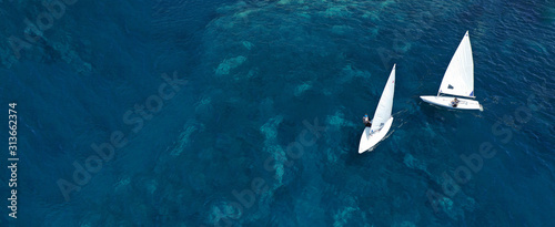 Aerial drone ultra wide photo of children practising with small sail boats in Mediterranean bay with deep blue sea