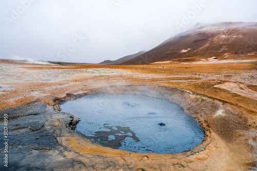 Bubbling geothermal hot/mud pool in the Hverarond area near Myvatn in the Icelandic landscape. Colorful and textured volcanic mineral rich sulphur ground infront.