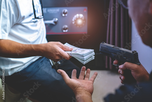 Armed robber using the gun to robbery the money with safe background.