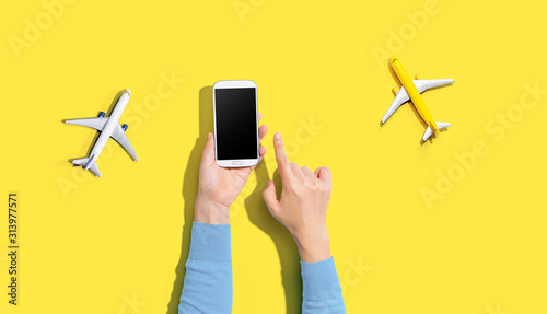 Person holding a smart phone with airplanes from above