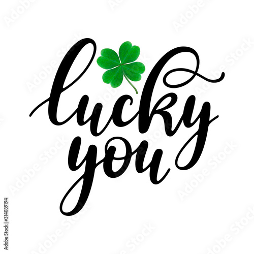 Lucky you - black handwritten lettering with four-leaf shamrock isolated on white background. 17 March St. Patrick's, Valentine's Day artwork. Good for greeting cards, t-shirt, and mug design.