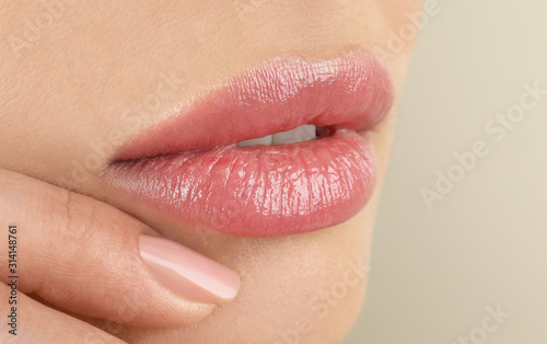 Woman with beautiful full lips on beige background, closeup