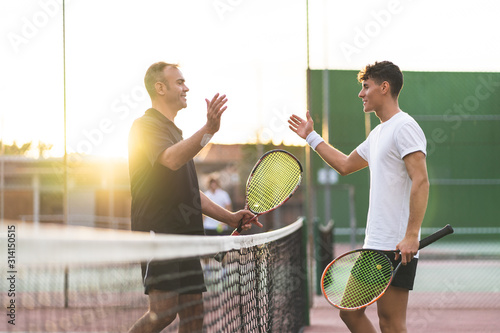 Father and Son Playing Tennis Outdoors.