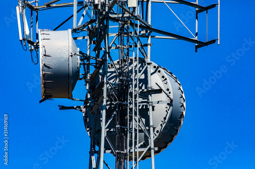 A closeup and detailed view of a cellular network base station with microwave antenna fixed to metal pylon, cause of electromagnetic pollution