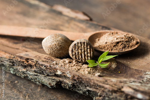 Dried seeds of fragrant nutmeg and grated nutmeg on wooden background.