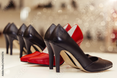 Collection of high-heels leather shoes standing in a row on a shelf in a store.