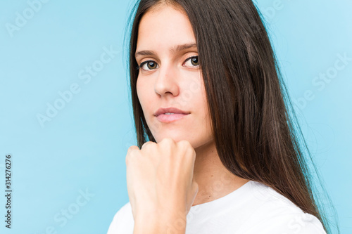 Young caucasian girl face closeup isolated in a blue background